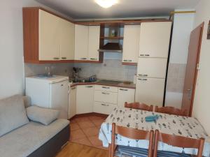 a small kitchen with white cabinets and a table with chairs at Apartma Marea in Izola