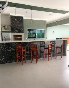 a kitchen with a bar with wooden stools at Casa para temporada in Presidente Epitácio