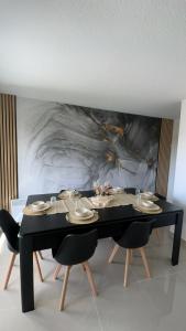 a black table with chairs and a painting on the wall at BY NEPTUNE - Appartement Disneyland Paris in Chessy