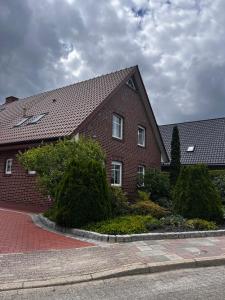 ein rotes Backsteinhaus mit Büschen davor in der Unterkunft Ferienwohnung Angela in Papenburg