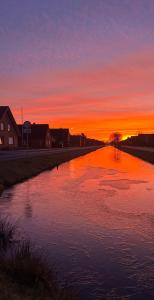 ein Wasserkörper mit Sonnenuntergang im Hintergrund in der Unterkunft Ferienwohnung Angela in Papenburg