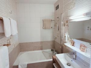 ein Badezimmer mit Badewanne und Waschbecken in der Unterkunft Hotel Perdrix in Super Besse + 32 Fotos