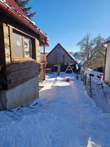 a snow covered driveway next to a house with a barn at Chalupa nad sadom in Liptovská Kokava