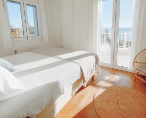 a white bedroom with a bed and a window at KALAMIES - Secluded Beach Apartments in Skala