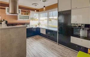 a kitchen with white appliances and blue cabinets at Awesome Home In Mragowo With Lake View in Mrągowo