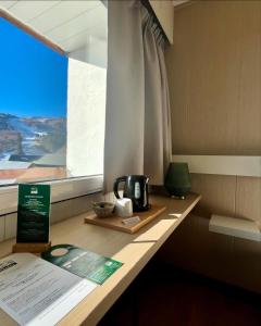 einen Tisch mit einem Wasserkocher neben einem Fenster in der Unterkunft Hotel Perdrix in Super Besse