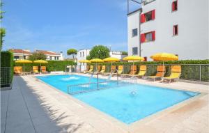 ein Pool mit Sonnenschirmen und Stühlen sowie ein Gebäude in der Unterkunft Nice Apartment In Cavallino-Treporti in Cavallino-Treporti + 19 Fotos