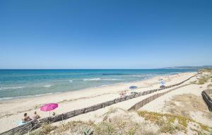 a beach with people and umbrellas and the ocean at 2 Bedroom Beautiful Home In Castelsardo in Castelsardo