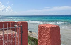 a red fence with the ocean in the background at 2 Bedroom Beautiful Home In Castelsardo in Castelsardo