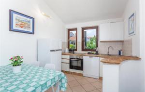 een keuken met witte kasten en een tafel met een tafelkleed bij Awesome Apartment In Pinezici With Wifi in Pinezici