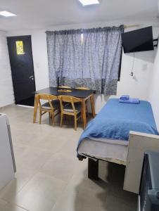 Un dormitorio con una cama y una mesa y una ventana. en Pasaje Del Rey, en El Bolsón