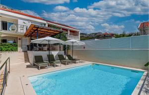 a swimming pool with chairs and umbrellas next to a house at Stunning Home In Viganj in Viganj