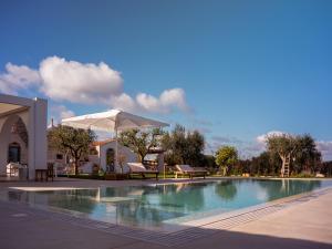 a swimming pool with an umbrella and a table and chairs at Trulli di V E N E R E in Castellana Grotte