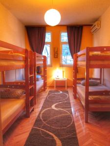 Habitación con 3 literas y alfombra. en Hostel Taso's House, en Mostar