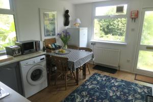 Fuchsia Cottage في Porthallow: مطبخ مع طاولة وكراسي وغرفة غسيل