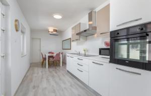 a kitchen with white cabinets and a table at 3 Bedroom Amazing Home In Pula in Pula