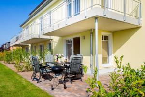 a patio with a table and chairs in front of a house at Ferienwohnung Sommerwind in Börgerende-Rethwisch