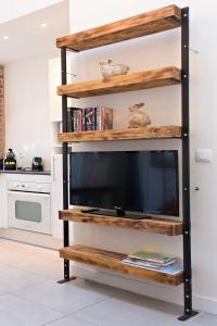 um suporte de televisão com prateleiras de madeira numa cozinha em Le Loft em Honfleur