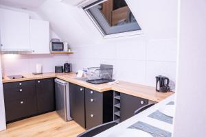 une cuisine avec des armoires noires et une fenêtre dans l'établissement Évasion urbaine studio moderne à Chalon - BY PRIMO C0NCIERGERIE, à Chalon-sur-Saône 5 autres photos