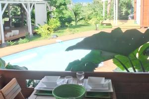 a table with plates on it next to a swimming pool at Bungalow charmant à Vincendo avec piscine partagée in Saint-Joseph