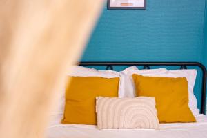 - un lit avec des oreillers jaunes et un mur bleu dans l'établissement Évasion urbaine studio moderne à Chalon - BY PRIMO C0NCIERGERIE, à Chalon-sur-Saône