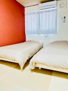 two beds in a room with a red wall at MA House in Osaka +77 photos