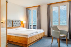 una camera da letto con un letto, una sedia e finestre di Hotel Strandhotel a Iseltwald