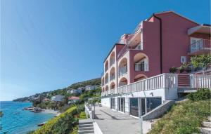 a pink building on a hill next to the water at One-Bedroom Apartment In Stanici in Celina