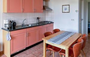 a kitchen with red cabinets and a wooden table at Amazing Home In De Moer in De Moer