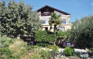 a large white building with a palm tree in front of it at Apartment Alojzija Stepinca Iii in Starigrad-Paklenica
