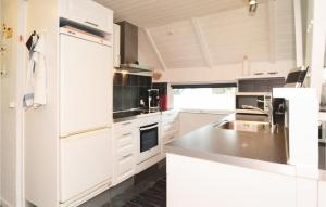 Una cocina blanca con fregadero y refrigerador. en Holiday Home Møllehusvej Blåvand Xi, en Blåvand