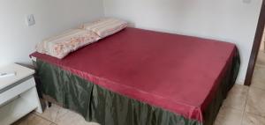 un lit dans une chambre avec une couverture rouge dessus dans l'établissement Apartamento térreo 01 quarto, à Torres