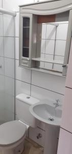 une salle de bain blanche avec toilettes et lavabo dans l'établissement Apartamento térreo 01 quarto, à Torres