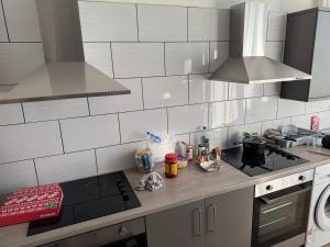 a kitchen with white tiled walls and stainless steel appliances at Barnsley Guesthouse in Barnsley