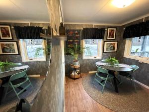 a dining room with two tables and chairs and windows at Haere Mai B&B Orust in Henån