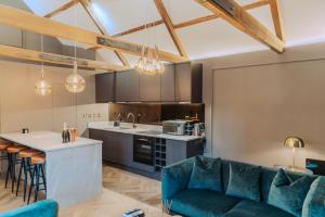 a living room with a blue couch and a kitchen at Magistrates Penthouse Suite - Town Centre Apartments with Spa in Morpeth