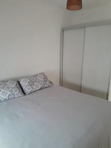 a white bed with two pillows on top of it at Departamento Rivadavia Sur in San Luis
