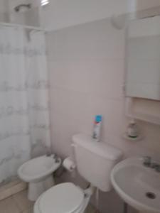 a white bathroom with a toilet and a sink at Departamento Rivadavia Sur in San Luis