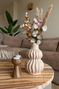 un jarrón blanco con flores en una mesa de café en Casa Buena Vista, en Egmond aan Zee