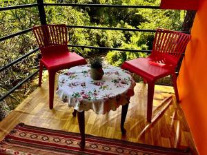 two red chairs and a table on a balcony at Little Bricks Reverside Villa by GreenEscapes in Vythiri +18 photos