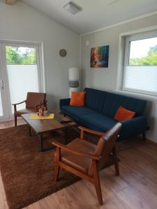a living room with a blue couch and a table at Chalet Ostfriesenruhe in Großefehn 