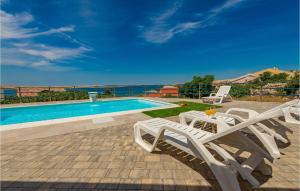 basen z 2 białymi leżakami obok basenu w obiekcie Awesome Apartment In Kustici, Novalja w mieście Kustići