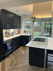 a kitchen with black cabinets and a white counter top at Parkgate Charming Cottage in Chelsfield
