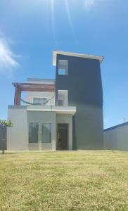 a building with a grass field in front of it at Casa do Bosque - Guriri-ES - 10 pessoas in São Mateus