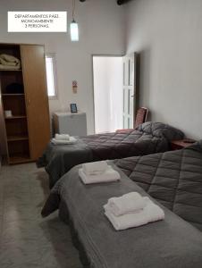 a room with three beds with towels on them at Departamentos PAEZ in Malargüe +4 photos