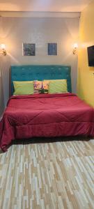 a bedroom with a bed with a red bedspread at Kikay's Bed & Breakfast in Tagaytay