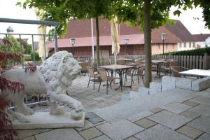 a statue of a lion on a patio with tables and chairs at Gasthof zum Löwen in Wilflingen in Langenenslingen