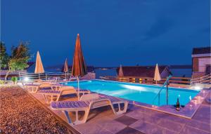 a swimming pool with lounge chairs and umbrellas at night at Apartment Pavlinka Bb Iv in Posedarje