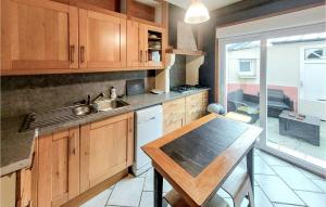 eine Küche mit Holzschränken, einer Spüle und einem Tisch in der Unterkunft Stunning Home In Grand-Fort-Philippe in Grand-Fort-Philippe