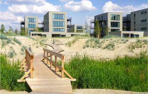 ein Holzsteg im Sand vor Gebäuden in der Unterkunft Beach Front Apartment in Lembruch